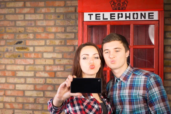 Pareja posando frente a una cabina telefónica británica —  Fotos de Stock