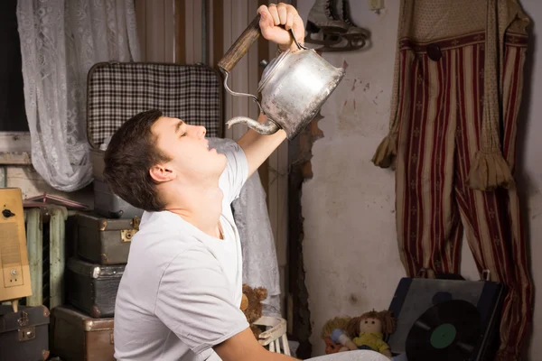 Jovem bebendo algo da chaleira vintage — Fotografia de Stock