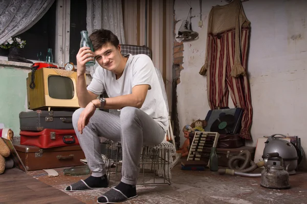 Joven macho en la sala de basura sosteniendo botella de vidrio —  Fotos de Stock