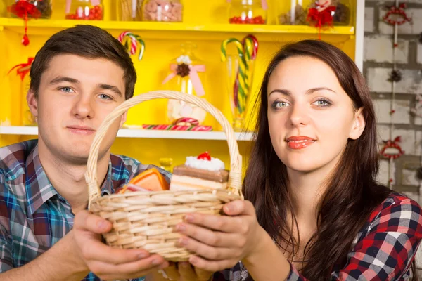 Pareja sonriente sosteniendo una cesta de mimbre de galletas —  Fotos de Stock