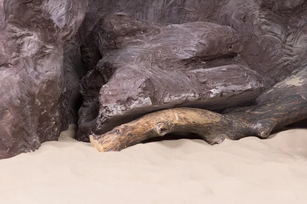 Künstliche Felsen mit Treibholz und Meeressand — Stockfoto