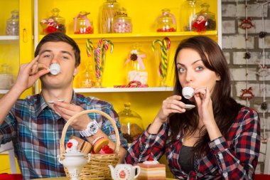 Couple Sipping a Drink From Small Cups at the Cafe clipart