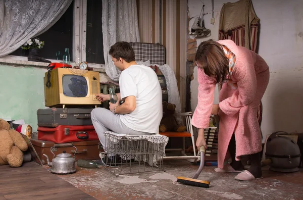 Pareja joven limpiando una habitación desordenada — Foto de Stock