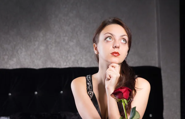 Задумчивая леди с цветком красной розы — стоковое фото