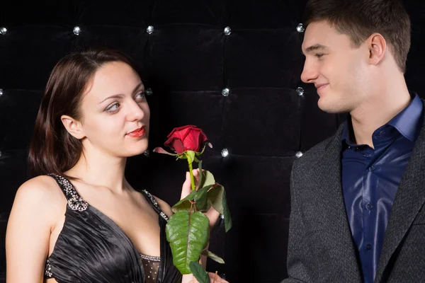 Casal amoroso sorrindo sobre uma rosa vermelha — Fotografia de Stock