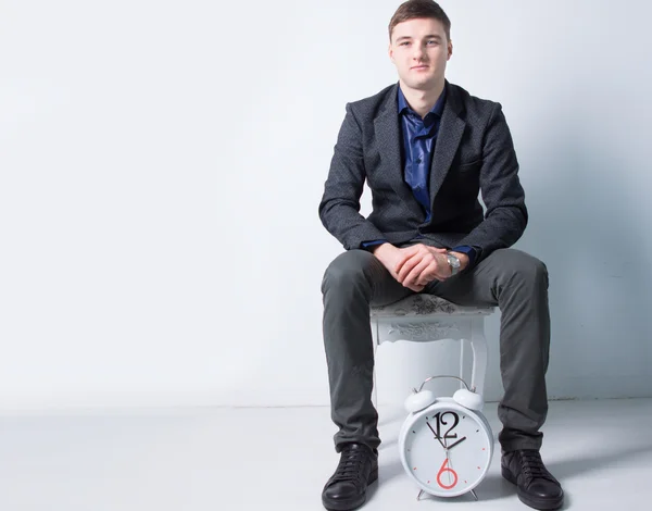 Sitzender junger Geschäftsmann mit Wecker — Stockfoto