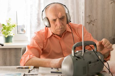 Serious Old Man Listening at Cassette Player clipart