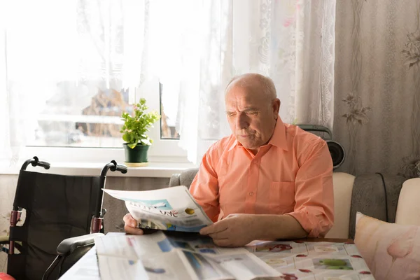 Sitzender glücklicher älterer Mann liest Zeitung — Stockfoto