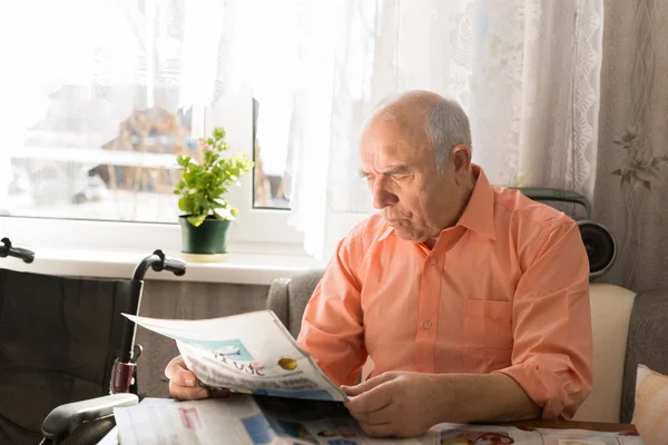 Сидящий пенсионер читает новости на таблоиде — стоковое фото