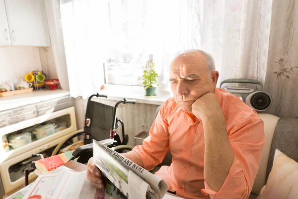 Enfocado sentado anciano leyendo periódico — Foto de Stock