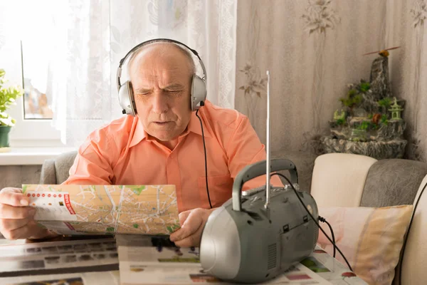 Viejo escuchando desde la radio mientras lee el tabloide — Foto de Stock