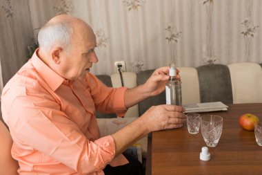 İhtiyar bir şişe şarap masanın üzerinde tutan