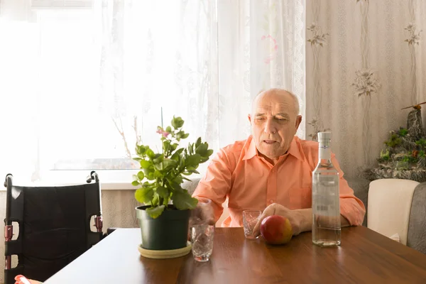 Старик за столом с вином, яблоками и растениями — стоковое фото