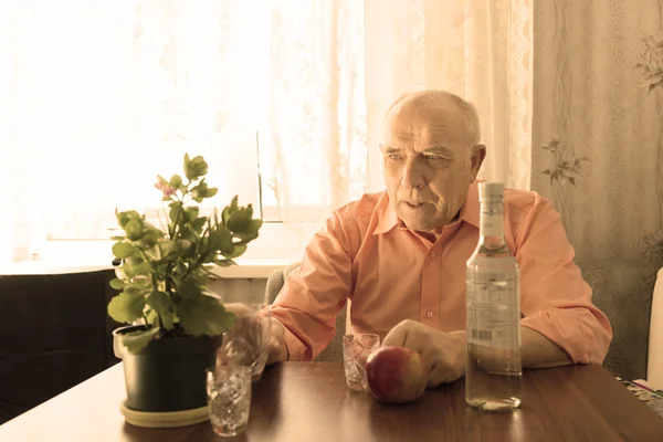 Velho bebendo homem olhando para planta na mesa — Fotografia de Stock