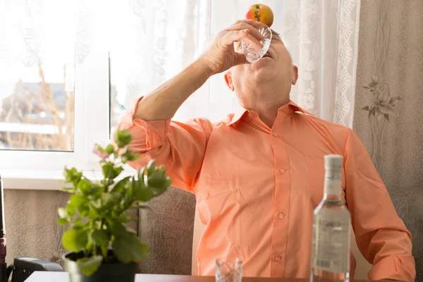 Verspielt trinkende Senioren mit Apfel auf der Stirn — Stockfoto