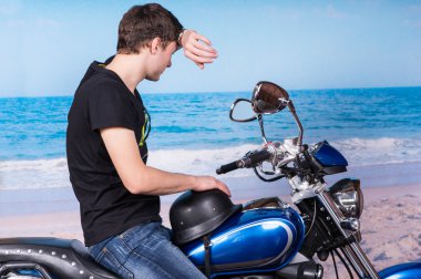 Adam alin kumsalda silerek motosiklet