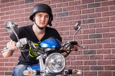 Genç adam siyah kask ile bir motosiklet sürme