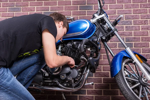 Jovem trabalhando em sua motocicleta azul personalizada — Fotografia de Stock