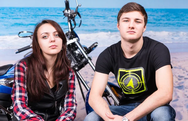 Casal sentado na frente de uma moto na praia — Fotografia de Stock