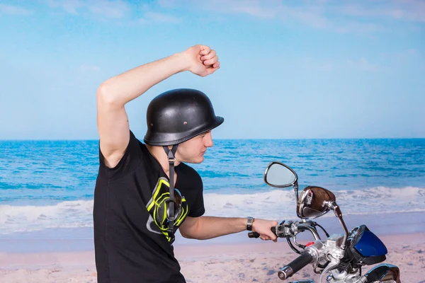 Homme à moto à la plage avec un bras levé — Photo