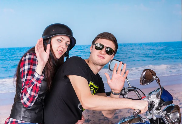 Casal na motocicleta acenando para câmera na praia — Fotografia de Stock