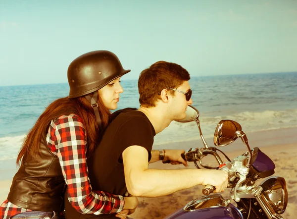 Retro paar rijden een motorfiets op het strand — Stockfoto