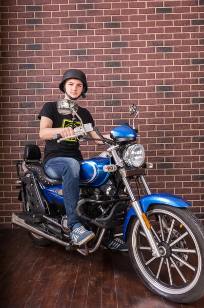 Retrato de hombre joven en motocicleta por pared de ladrillo — Foto de Stock