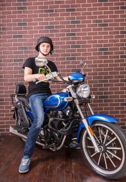 Jovem na motocicleta na frente da parede de tijolo — Fotografia de Stock