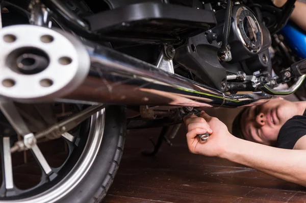 Mentiroso fixando sua moto usando a ferramenta chave inglesa — Fotografia de Stock