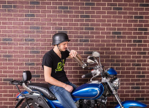 若い男が彼のバイクでアルコール飲料を座っています。 — ストック写真