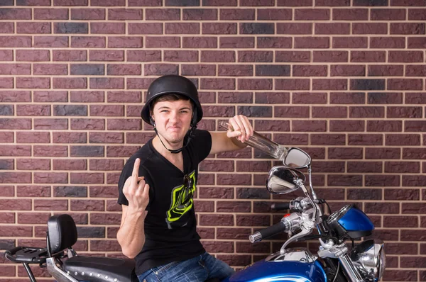 Молодой человек на мотоцикле подает палец в камеру — стоковое фото