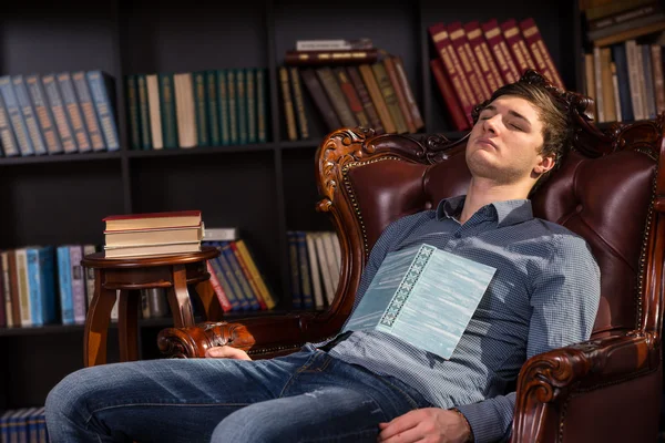 Jovem atraente dormindo em uma biblioteca — Fotografia de Stock