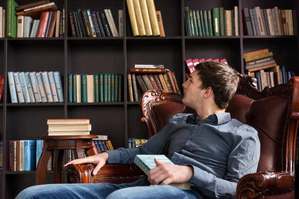 Jonge man boeken in een bibliotheek het uitchecken — Stockfoto