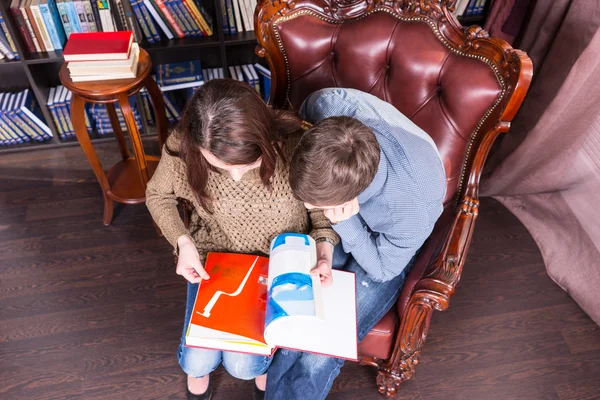 Paar auf einem Stuhl mit einem Buch in der Luft — Stockfoto