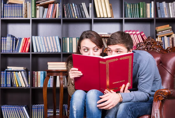 Amantes escondidos atrás de um livro olhando uns aos outros — Fotografia de Stock