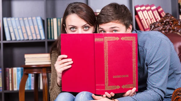 Młoda para zerkające przez książkę czerwony — Zdjęcie stockowe