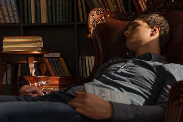 Joven durmiendo en la silla sosteniendo un libro —  Fotos de Stock