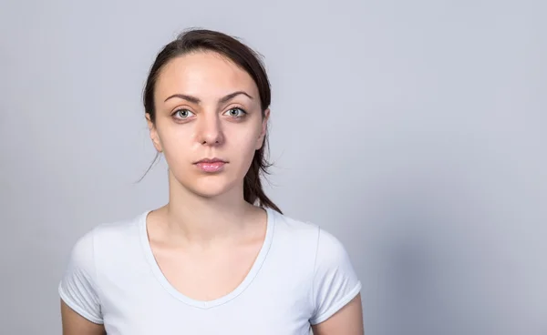 Ernstige jonge vrouw tegen witte achtergrond — Stockfoto