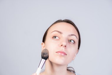 Yüzünde makyaj uygulamak düşünceli genç kadın