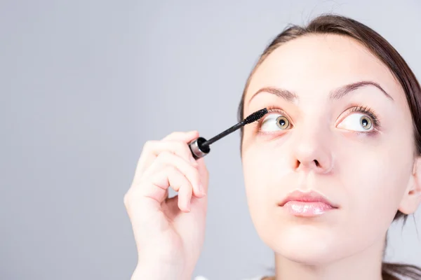 Mujer Aplicando maquillaje de máscara mientras se ve bien —  Fotos de Stock