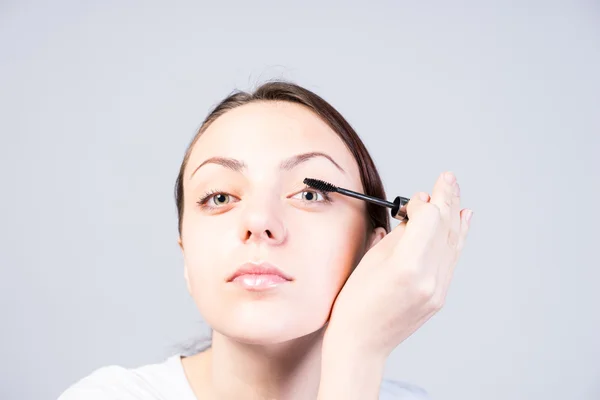 Frau trägt Wimperntusche auf, während sie in die Kamera schaut — Stockfoto