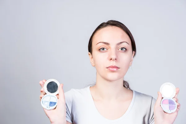 Mujer seria sosteniendo dos maquillaje fundación —  Fotos de Stock
