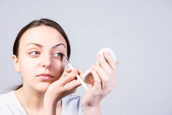 Žena použití tužka na oči při pohledu na zrcadlo — Stock fotografie