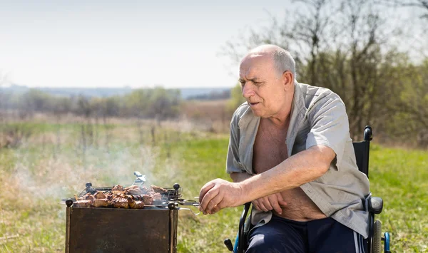 Homem envelhecido em sua cadeira de rodas Grilling Under the Sun — Fotografia de Stock