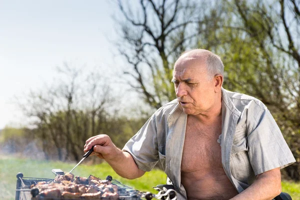 Viejo serio asando a la parrilla en el área del campamento — Foto de Stock