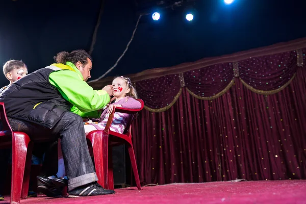 Man Applying Make Up to Girls Face on Empty Stage — Stock Photo, Image