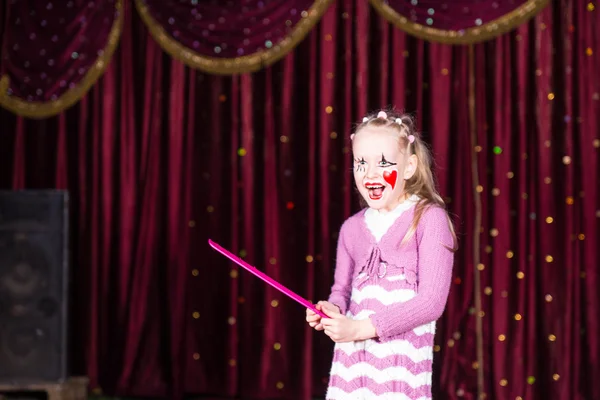 Девушка носит клоун макияж держа большой розовый гребень — стоковое фото