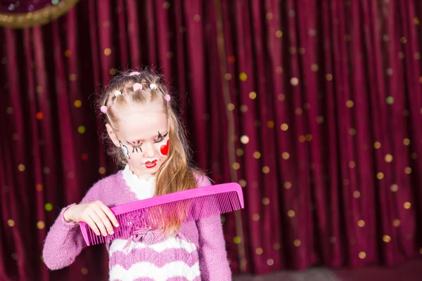 Jeune fille clown brossant les cheveux avec un grand peigne — Photo