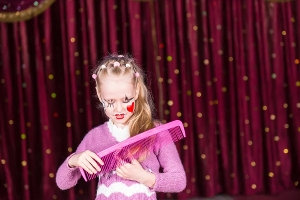 Jeune fille clown brossant les cheveux avec un grand peigne — Photo