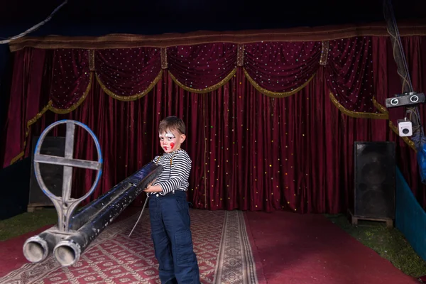 Junger Clown steht mit großer Waffe auf der Bühne — Stockfoto